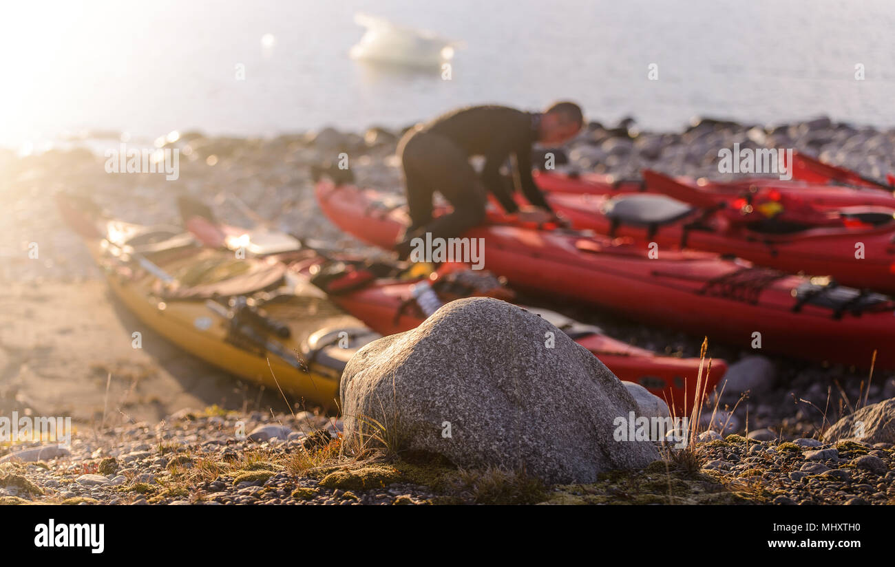 Man preparing sea kayak on beach, Narsaq, Kitaa, Greenland Stock Photo