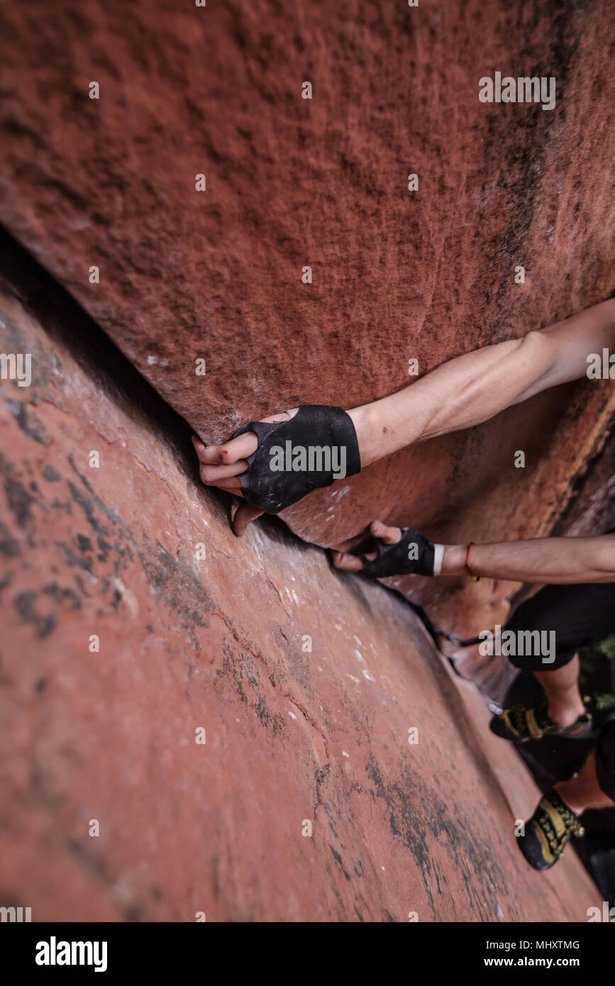 Rock climber climbing sandstone rock, hands gripping rock, elevated view, Liming, Yunnan Province, China Stock Photo
