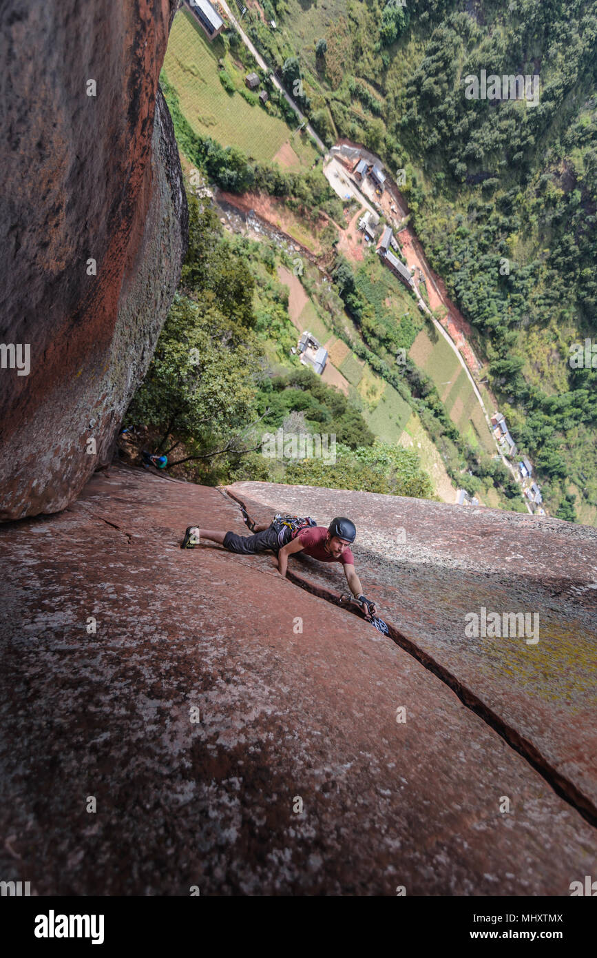 Rock climber climbing sandstone rock, elevated view, Liming, Yunnan Province, China Stock Photo