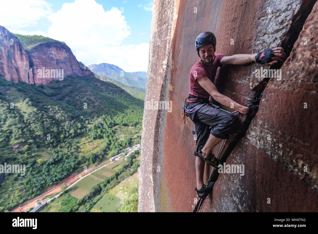 Rock climber climbing sandstone rock, Liming, Yunnan Province, China