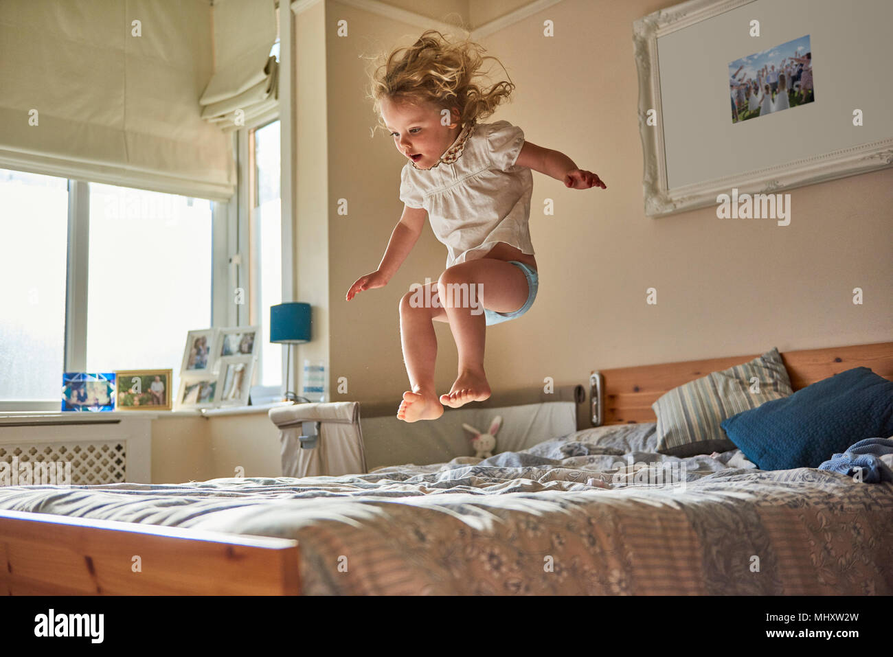 Female toddler jumping mid air on bed Stock Photo