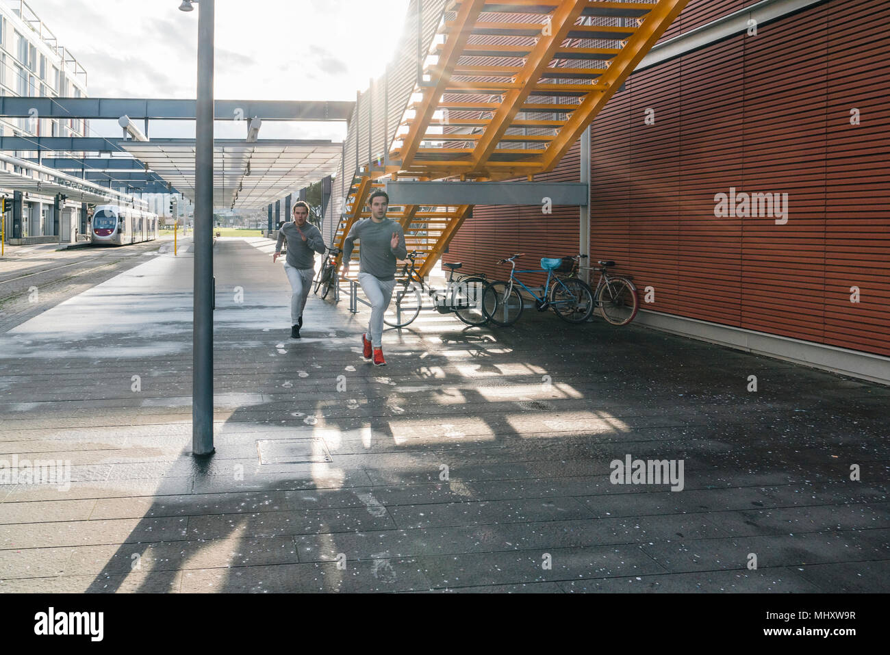 Young adult male twins running together, running in city Stock Photo