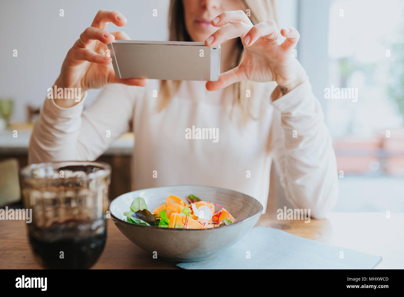 Woman taking photo of vegan meal in restaurant Stock Photo