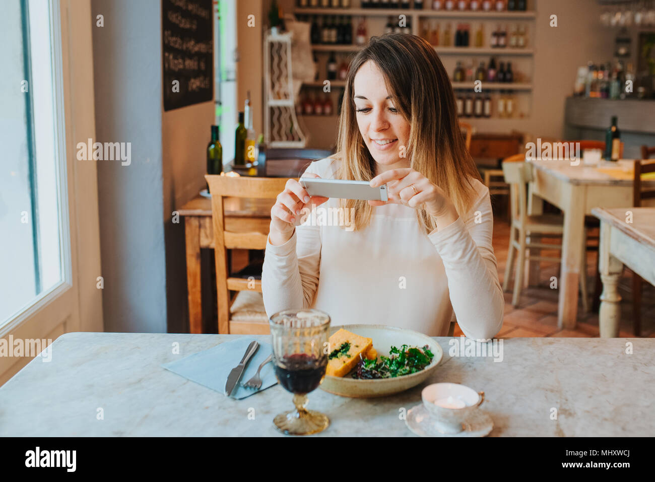 Woman taking photo of vegan meal in restaurant Stock Photo