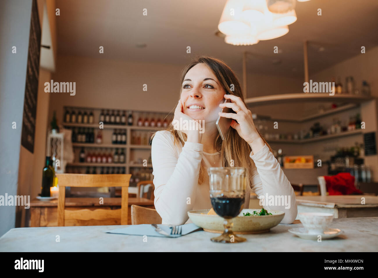 Woman using mobile while having vegan meal in restaurant Stock Photo