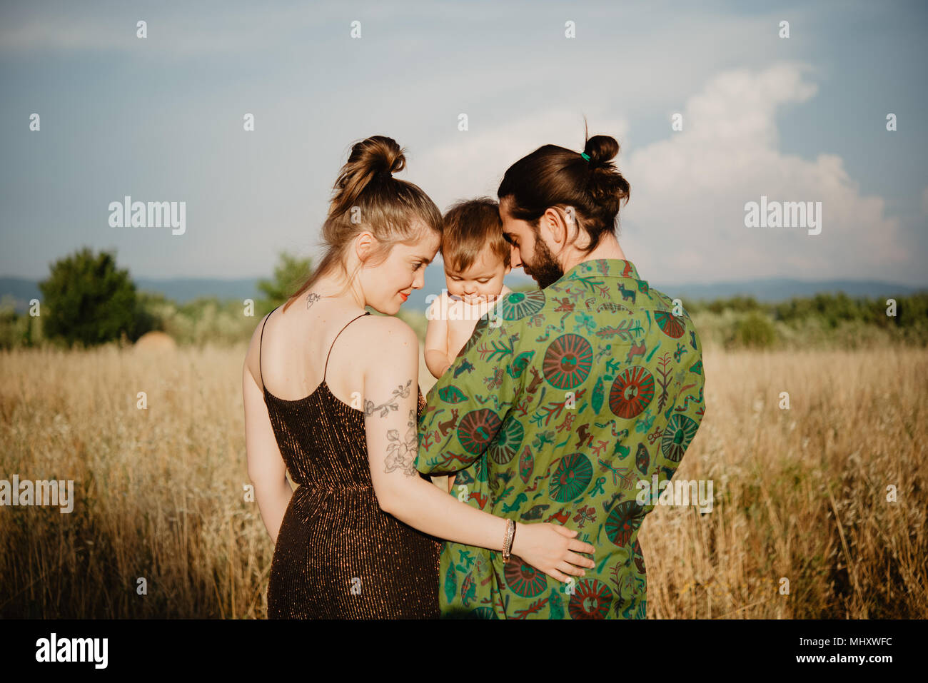 Couple with baby girl on golden grass field, Arezzo, Tuscany, Italy Stock Photo
