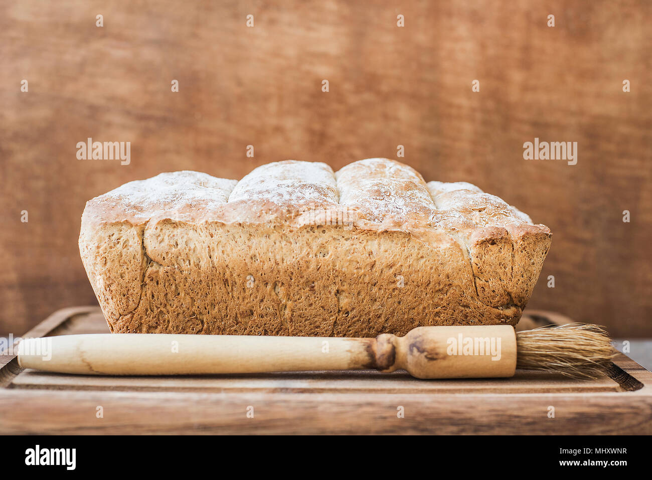 Freshly baked loaf of whole wheat bread on wooden surface Stock Photo