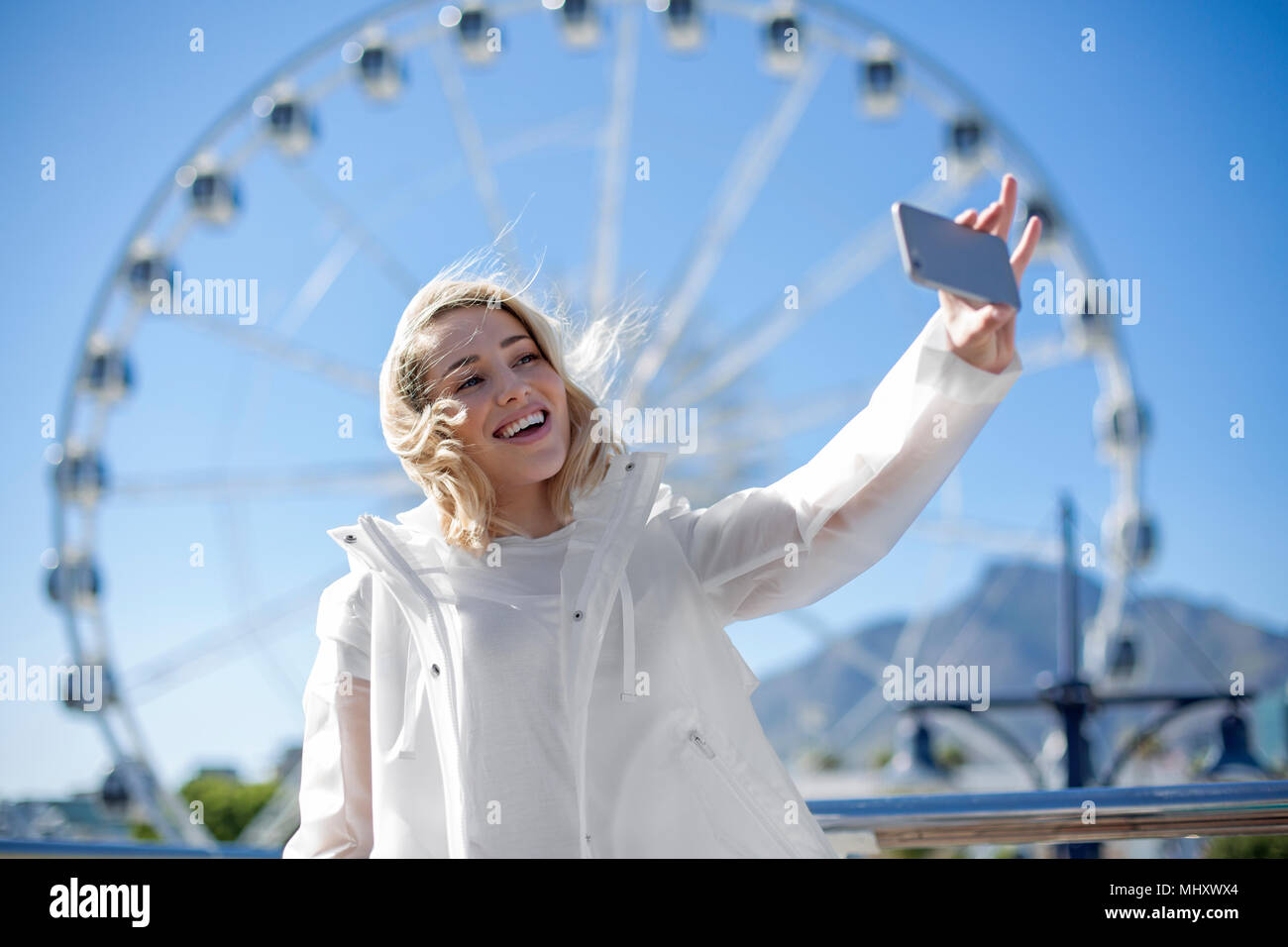 Woman taking selfie in front of Cape Wheel, Victoria and Alfred Waterfront, Cape Town, South Africa Stock Photo