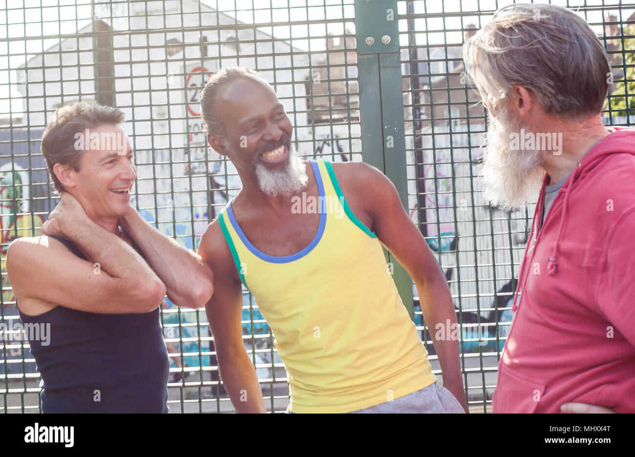 Three mature men in basketball court, laughing together Stock Photo