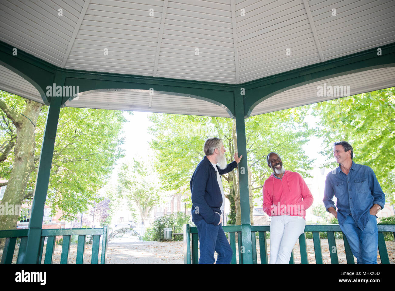 Three mature men standing under bandstand, talking Stock Photo