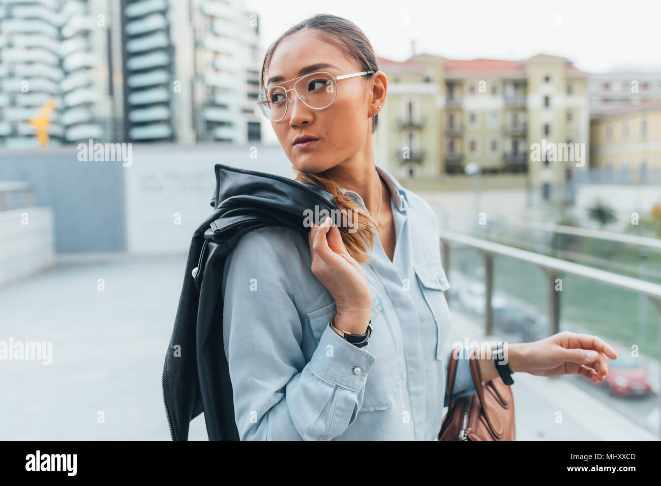 Portrait of businesswoman outdoors, carrying leather jacket over shoulder, looking away, pensive expression Stock Photo
