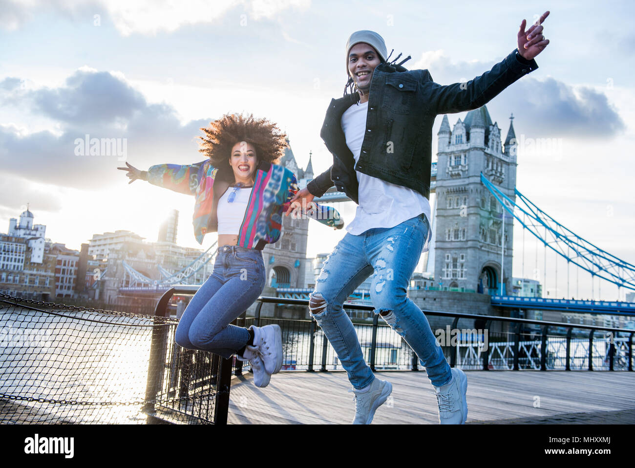 Young couple outdoors, jumping for joy, Tower Bridge in background, London, England, UK Stock Photo