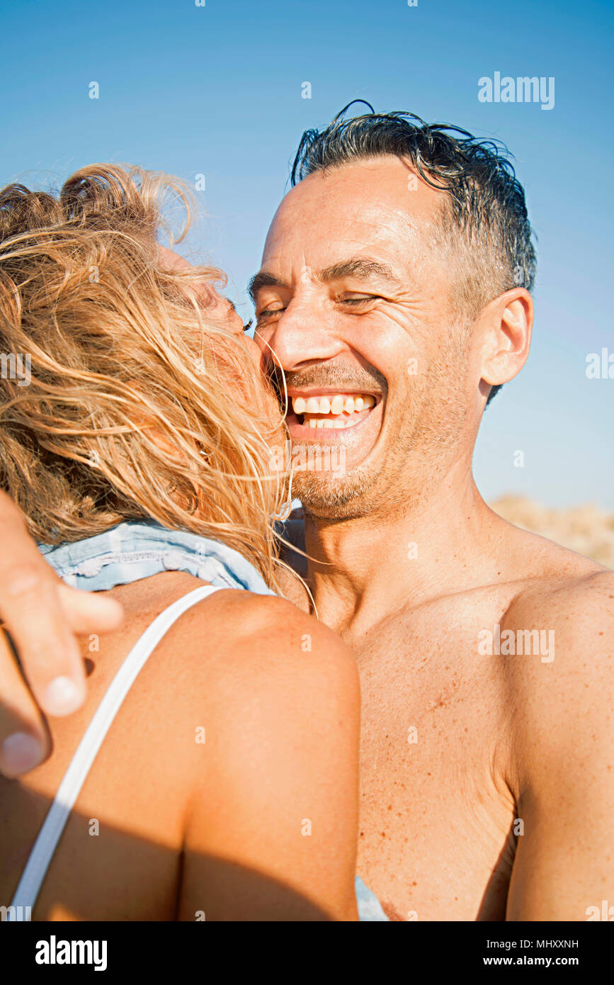 Mature couple on outdoors, wearing swimwear, hugging, laughing Stock Photo