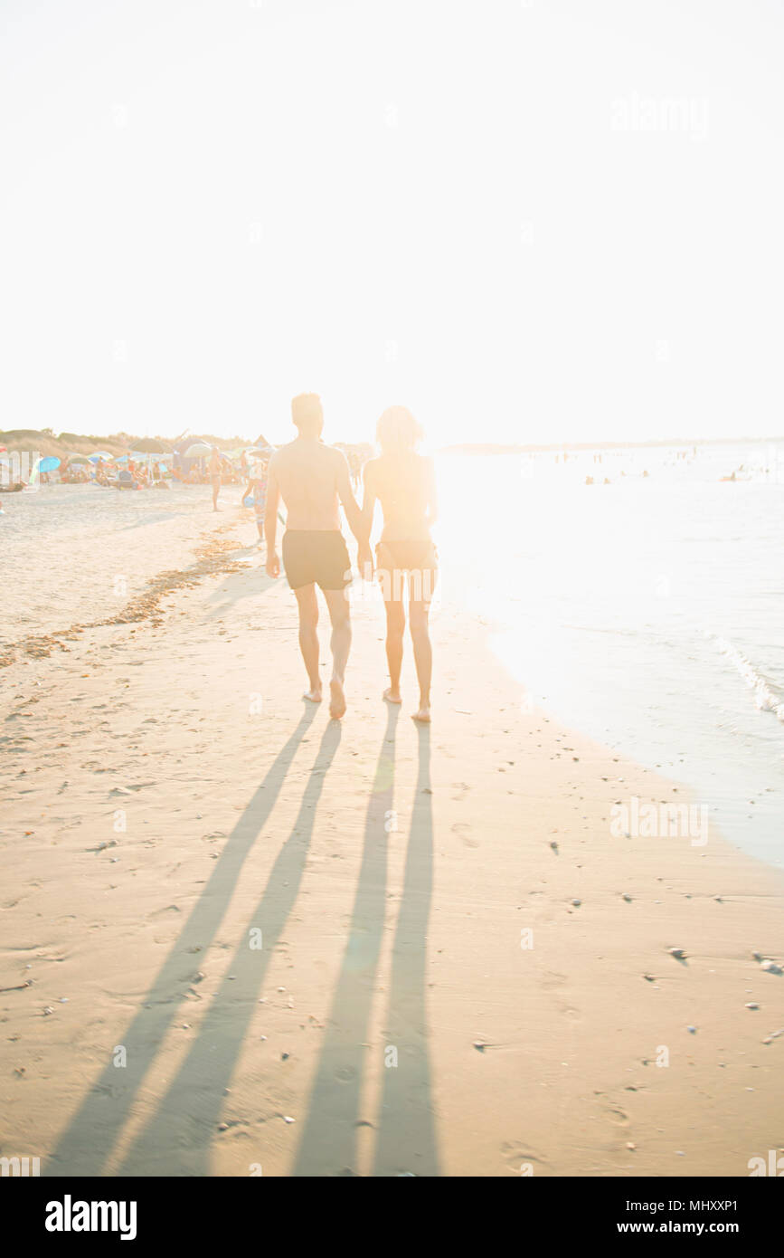 Mature couple walking on beach, holding hands, rear view Stock Photo