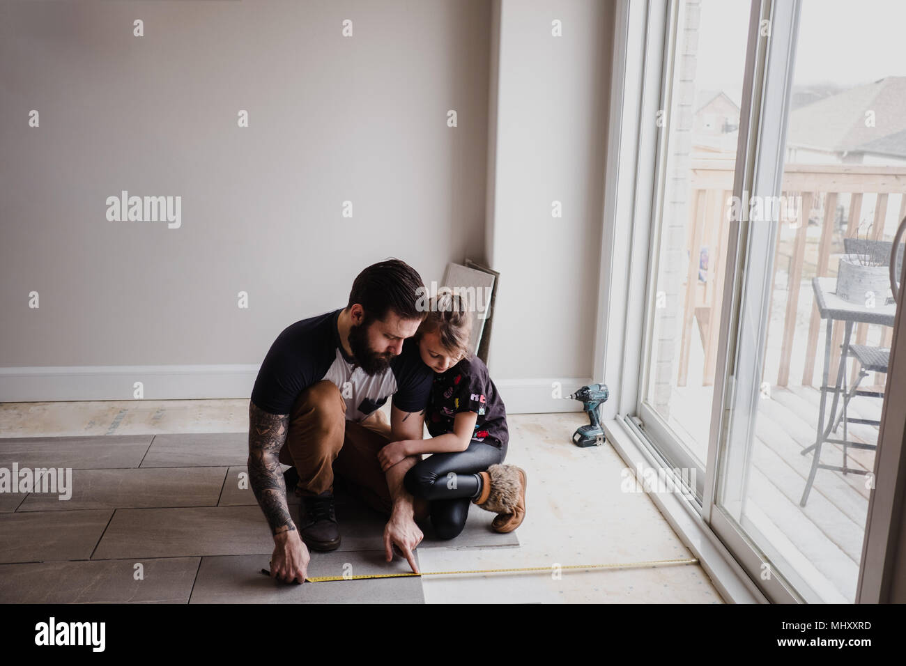 Girl helping father install floor tiles Stock Photo