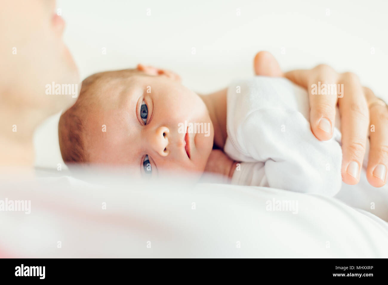 Baby boy lying down on fathers chest looking at camera Stock Photo