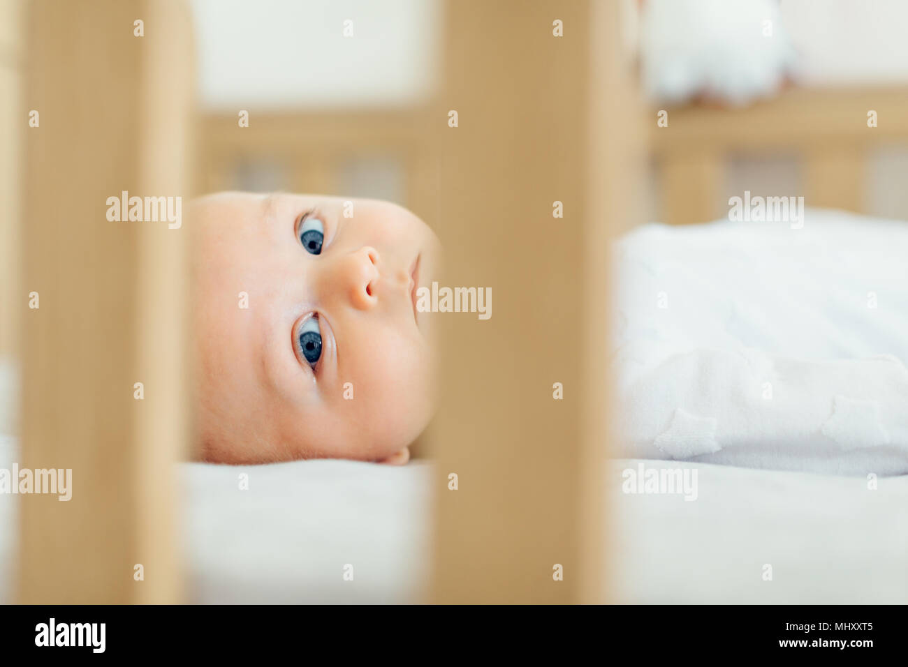 View through cot of baby boy lying down looking at camera Stock Photo