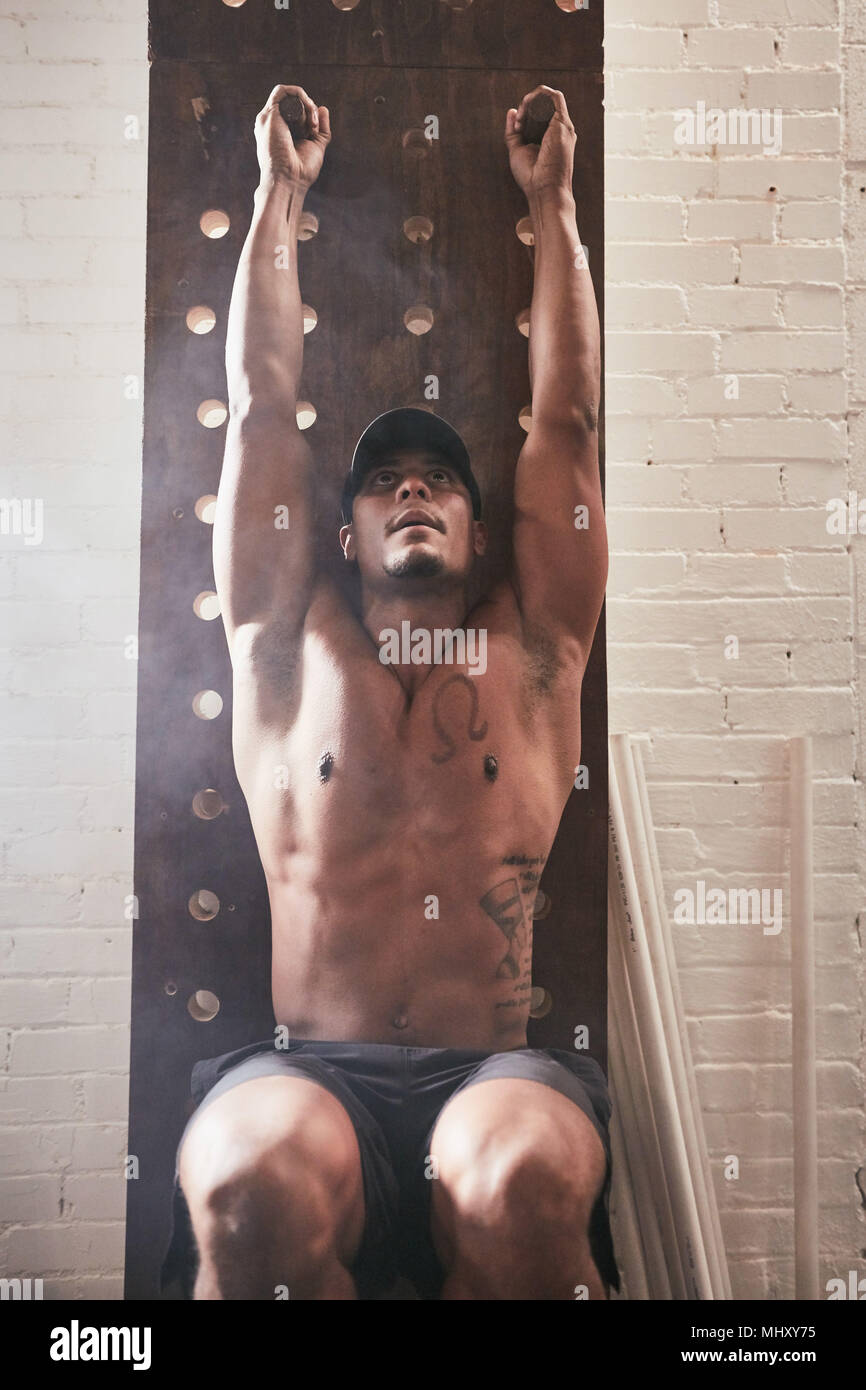 Man in gym using exercise equipment, doing leg pull ups Stock Photo