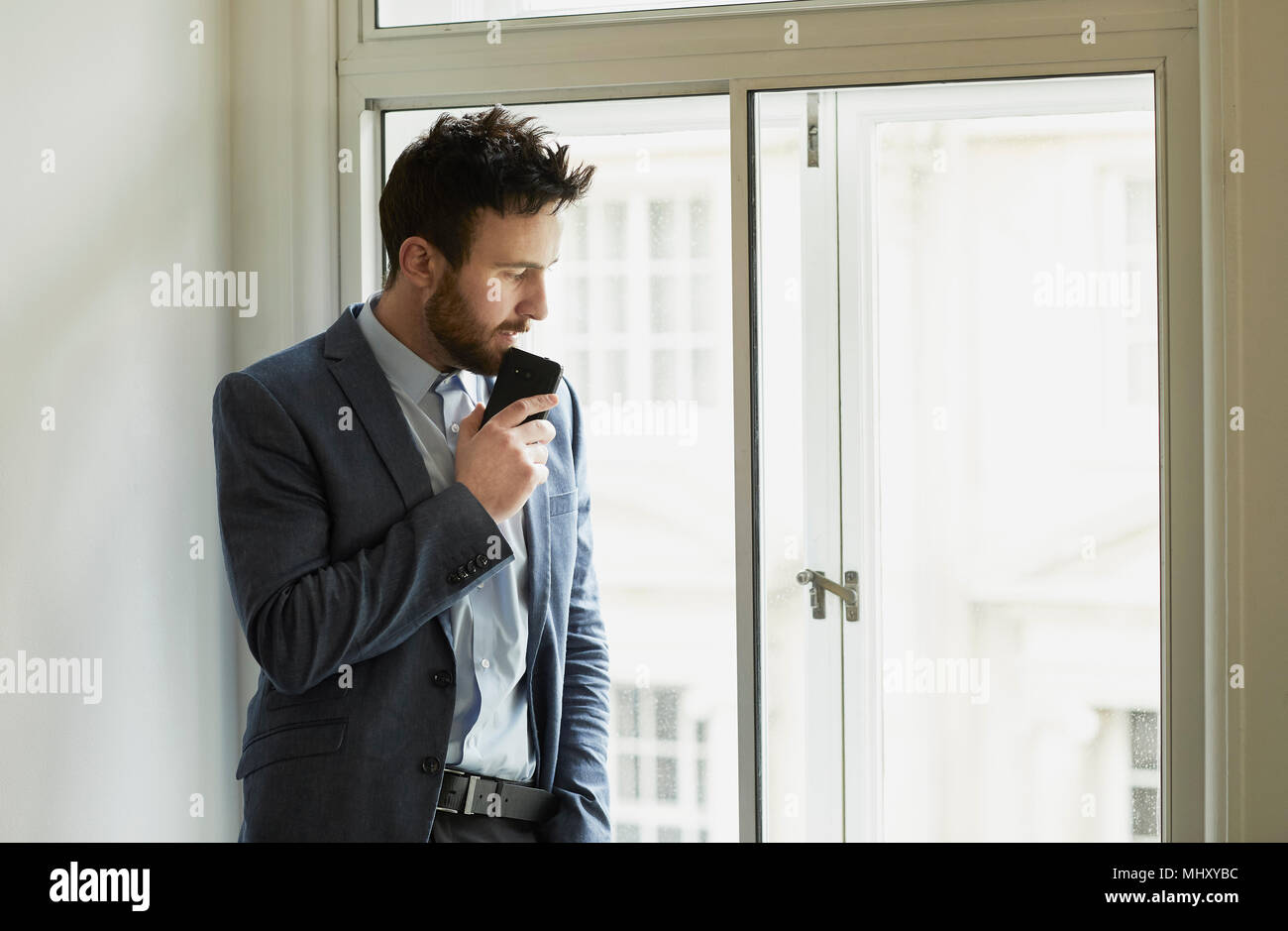 Businessman looking out of window pensively Stock Photo