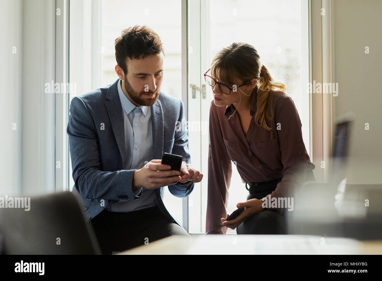 Colleagues in office looking at smartphone Stock Photo