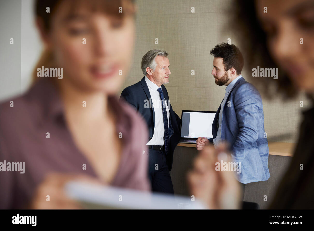 Colleagues in office chatting, focus on background Stock Photo