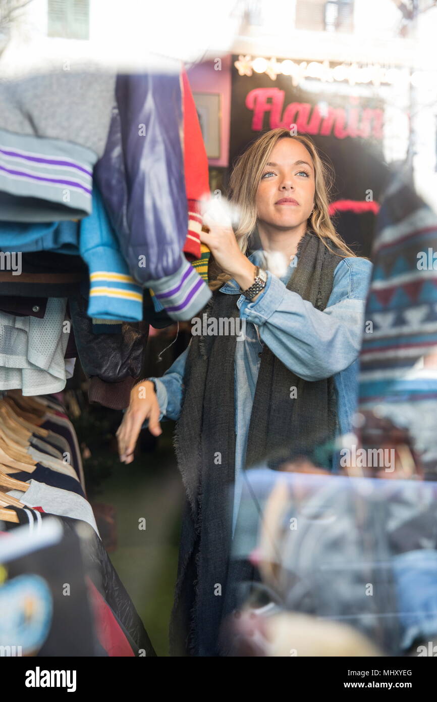 Young woman browsing vintage clothes in thrift store Stock Photo