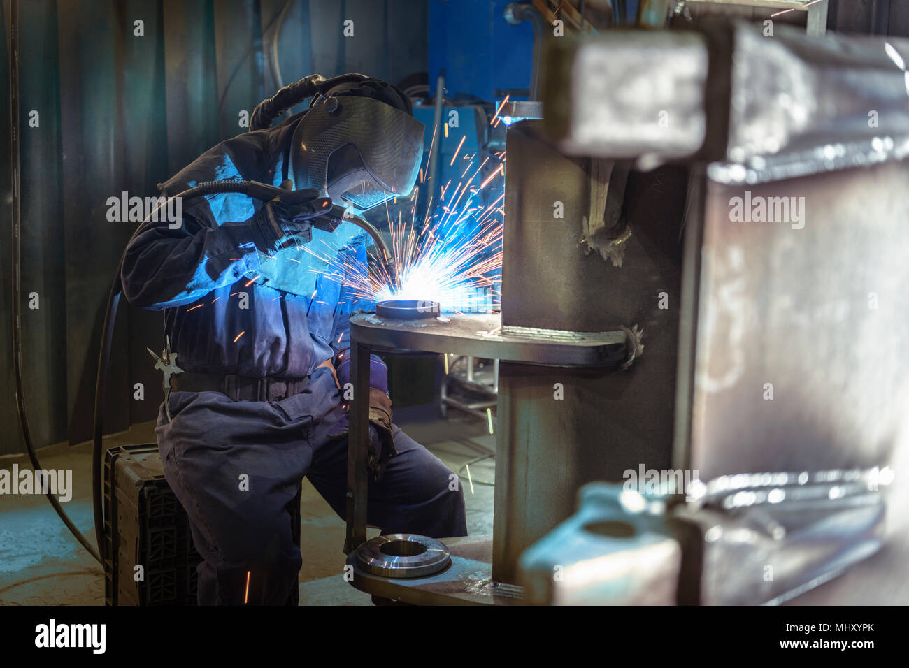 Welder welding part of digger bucket in engineering factory Stock Photo