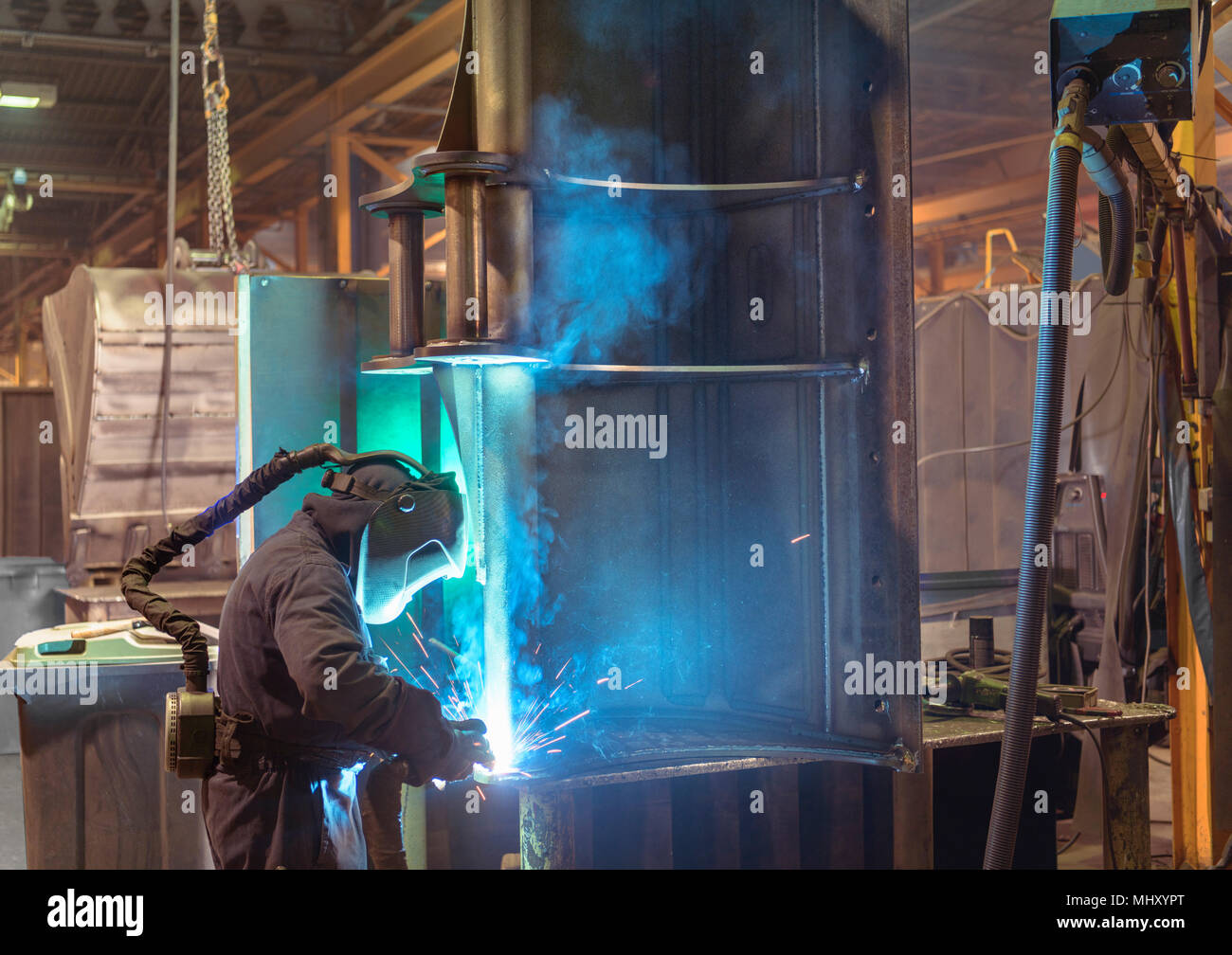 Welder welding part of digger bucket in engineering factory Stock Photo