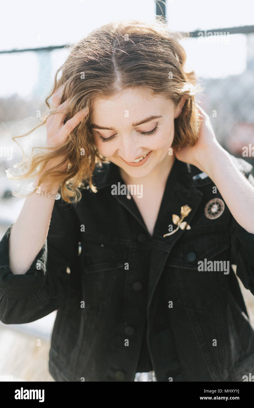 Portrait of woman wearing denim jacket with pin badges looking down smiling Stock Photo