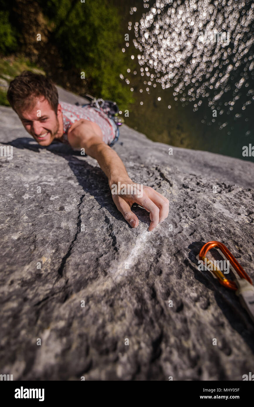 Young male rock climber reaching while climbing limestone rock face, Freyr, Belgium, high angle view Stock Photo