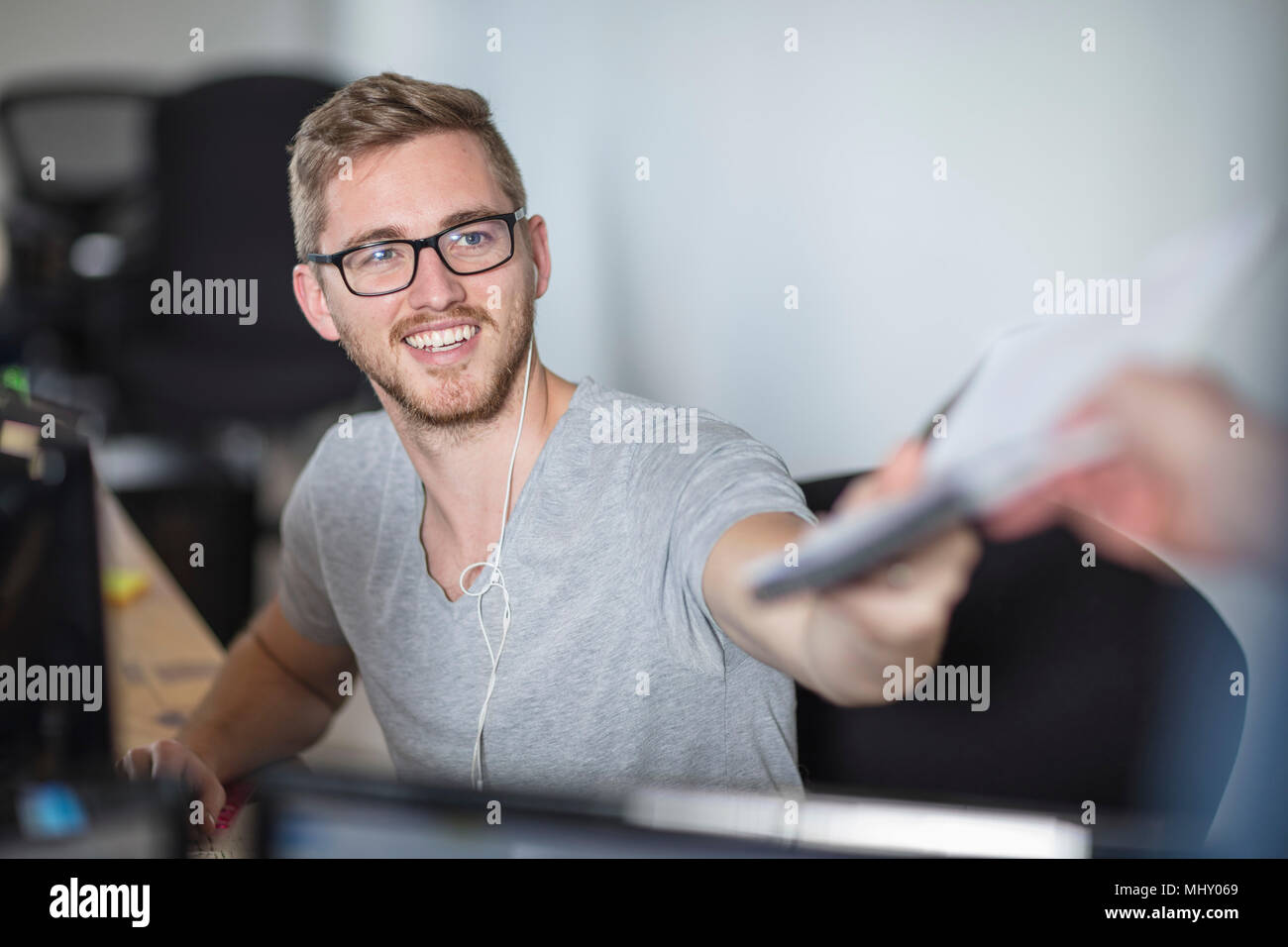 Young man handing paperwork to colleague in office Stock Photo