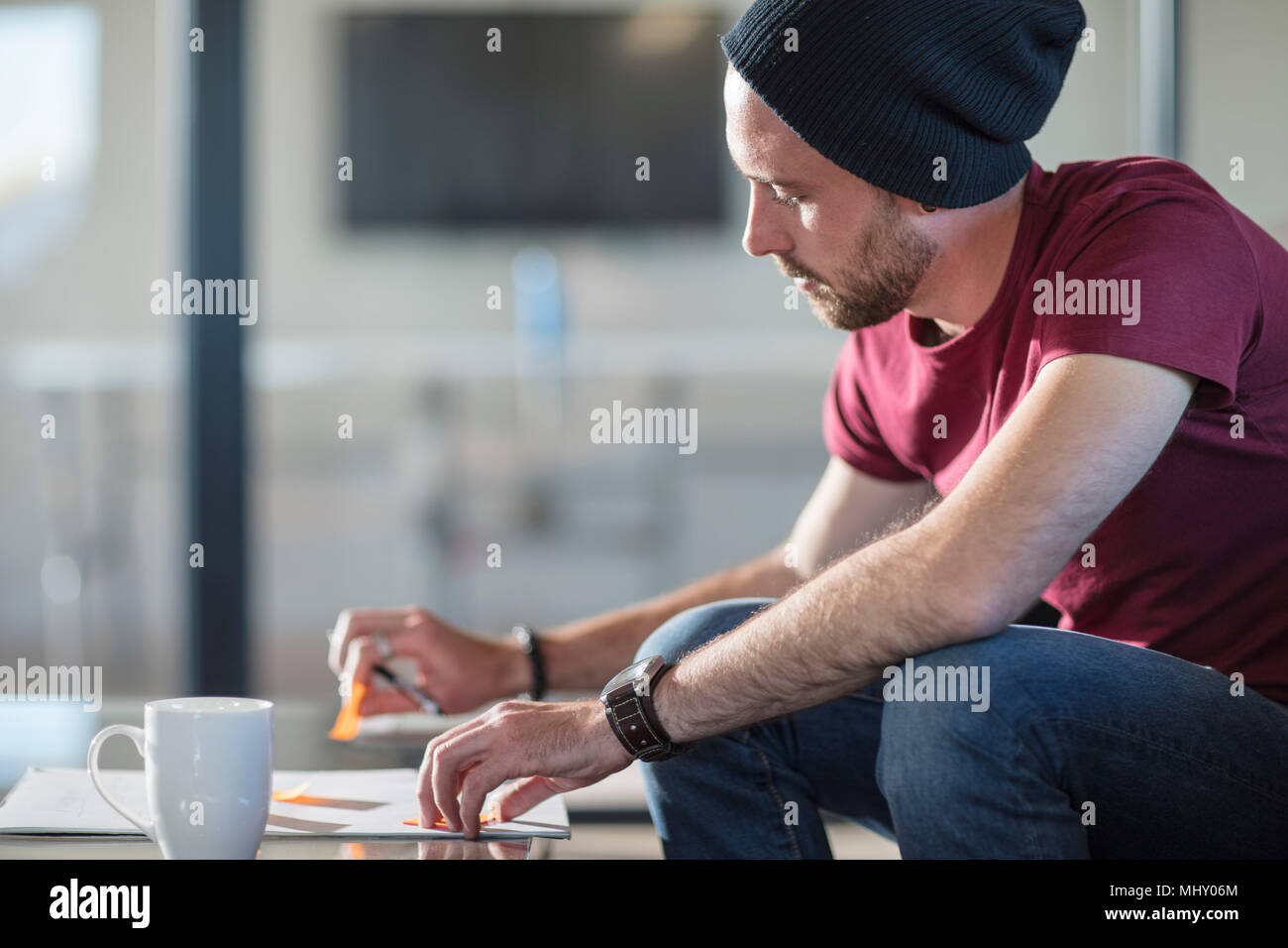 Young man making notes during coffee break in office Stock Photo