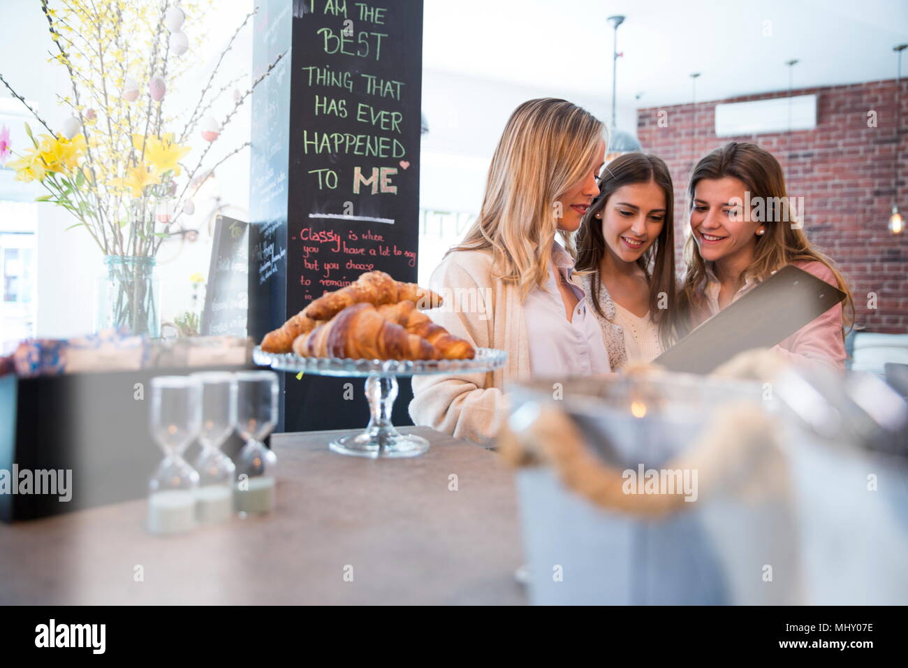 Three female friends, looking at menu in cafe Stock Photo
