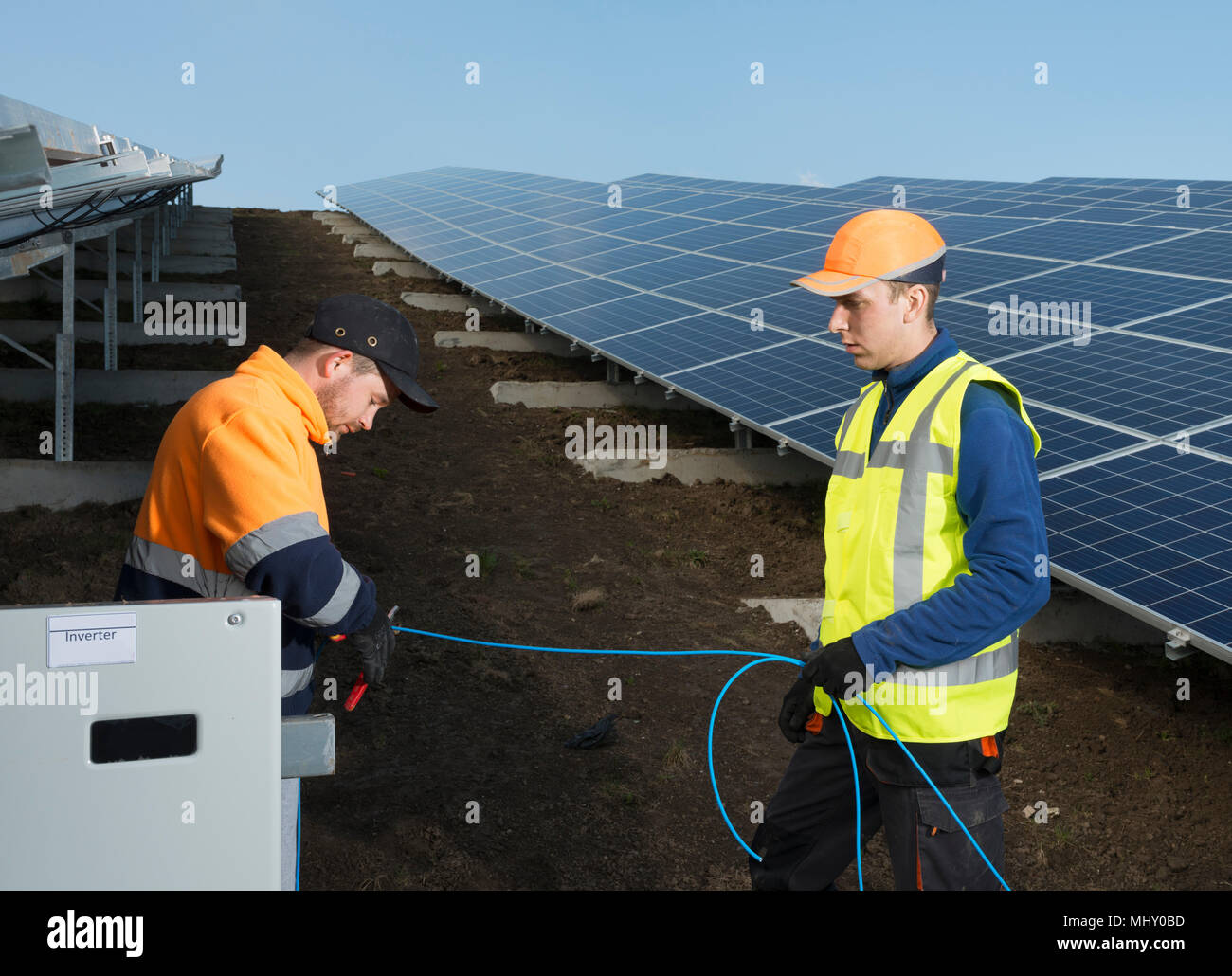 Engineers connecting solar panels on new solar farm, situated on former waste dump Stock Photo