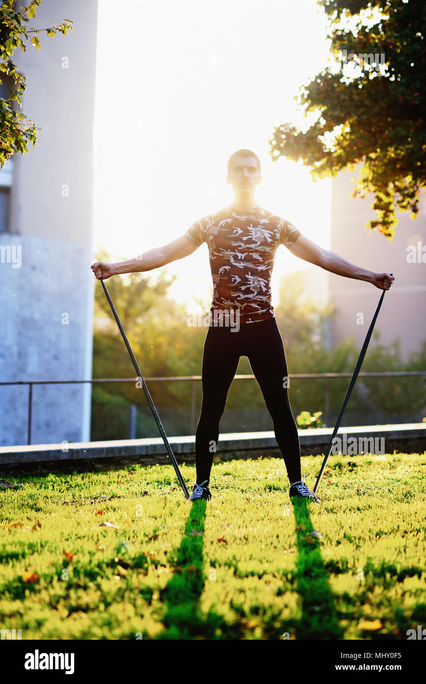 Young man exercising outdoors, using resistance bands Stock Photo
