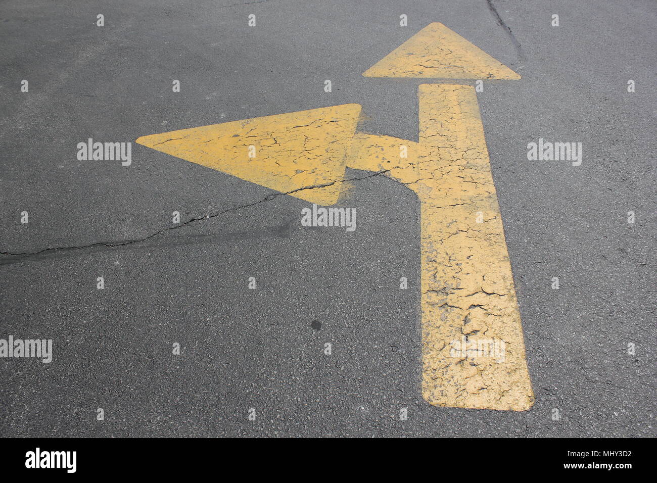 Yellow traffic arrow painted on the ground of a parking lot. Stock Photo