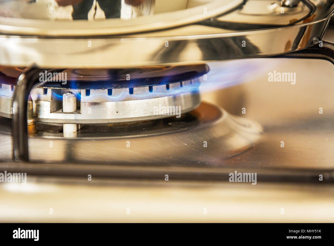 Focus of blue flame gas on a cooker boiling pot in kitchen gas stove. Cooking Food. Stock Photo