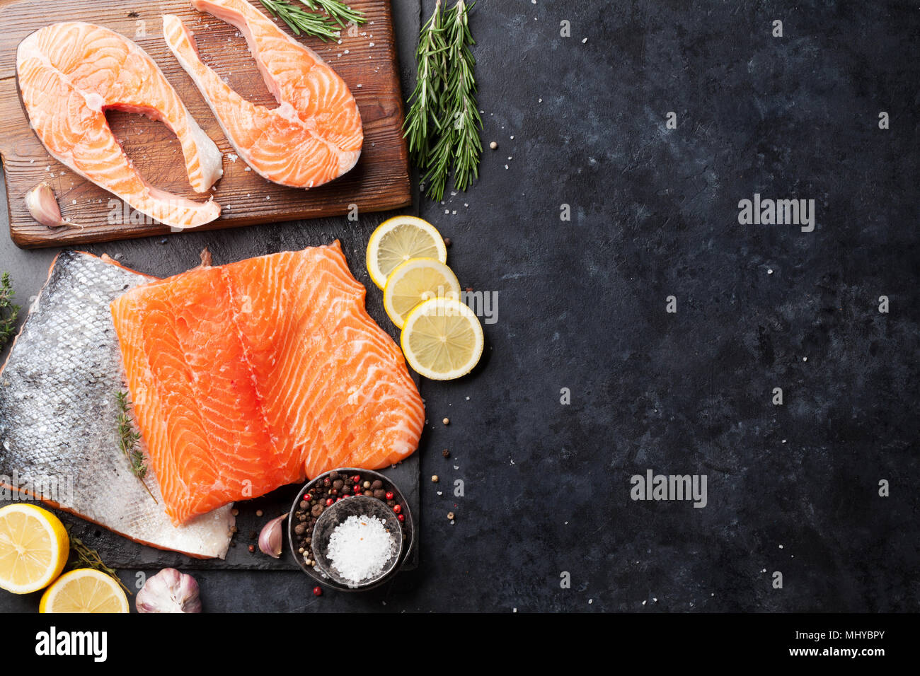 Raw salmon fish steaks with spices cooking on cutting board. Top view ...