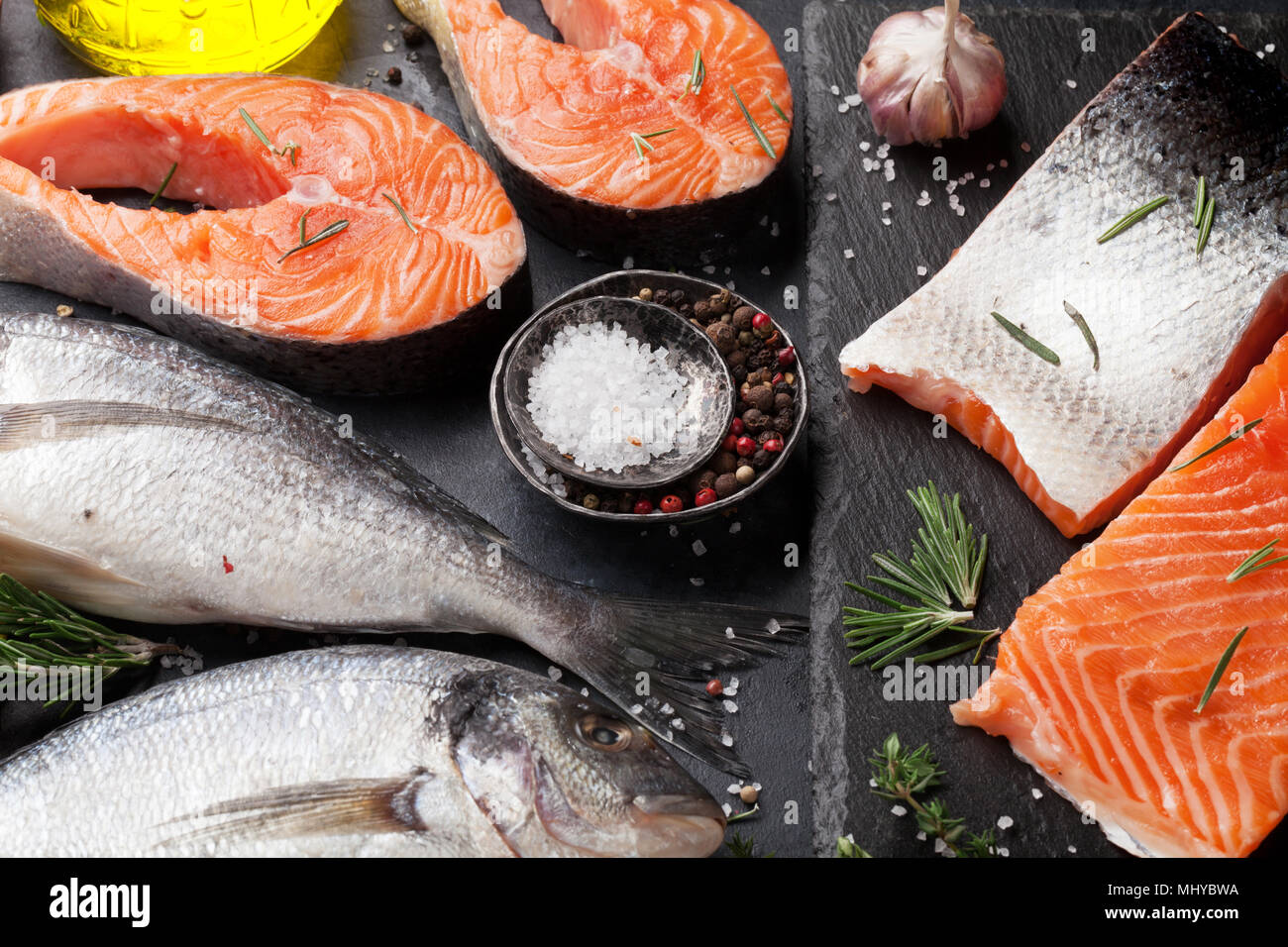 Raw salmon fish fillet and dorado with spices cooking on cutting board ...