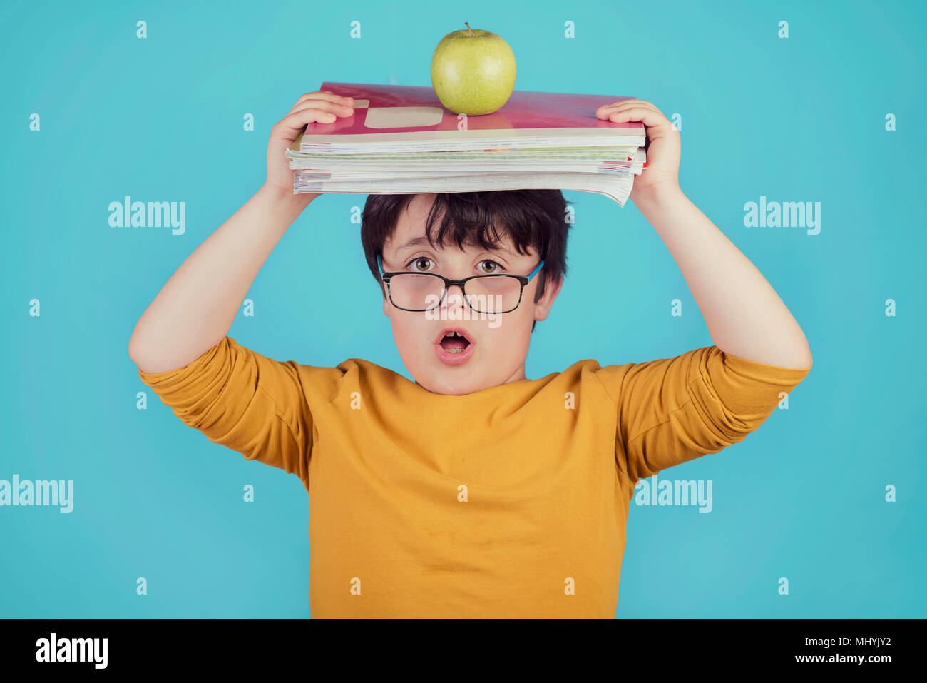 surprised boy with books and apple on blue background Stock Photo