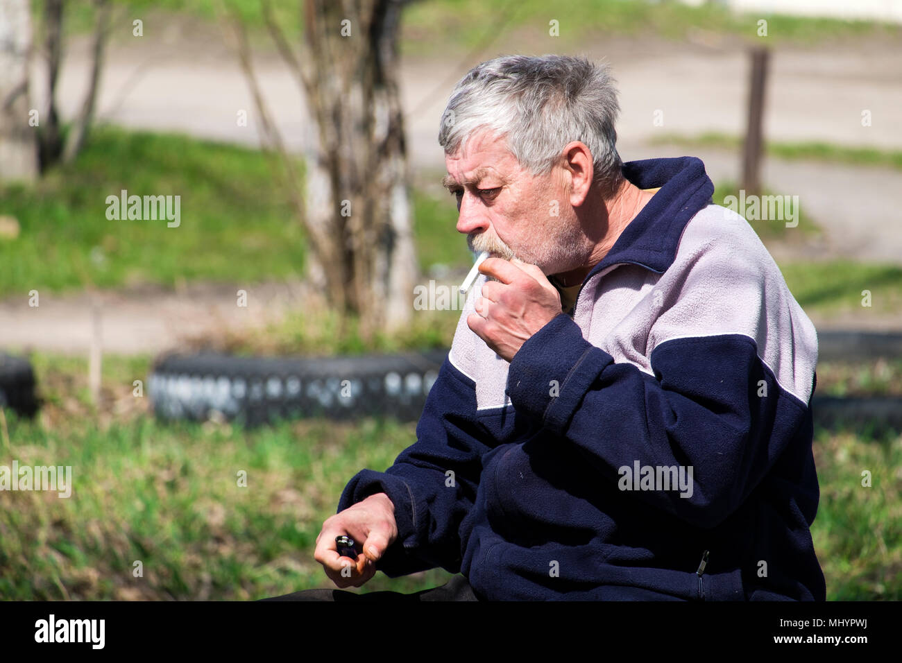 smoking a cigarette without a filter Gray-haired old bearded man smoking a cigarette without a filter Stock  Photo
