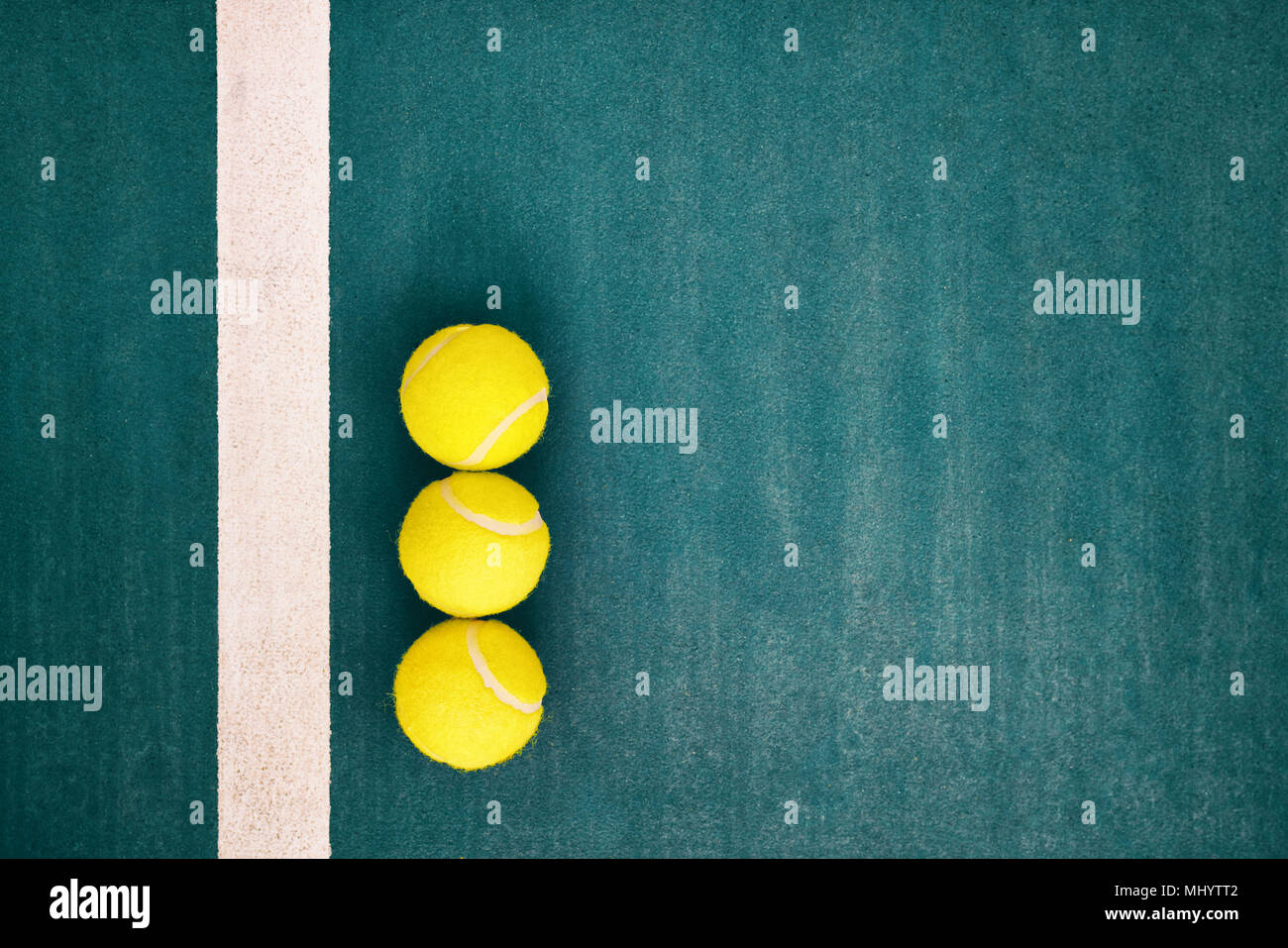 Yellow tennis balls near the line on green concrete tennis court with