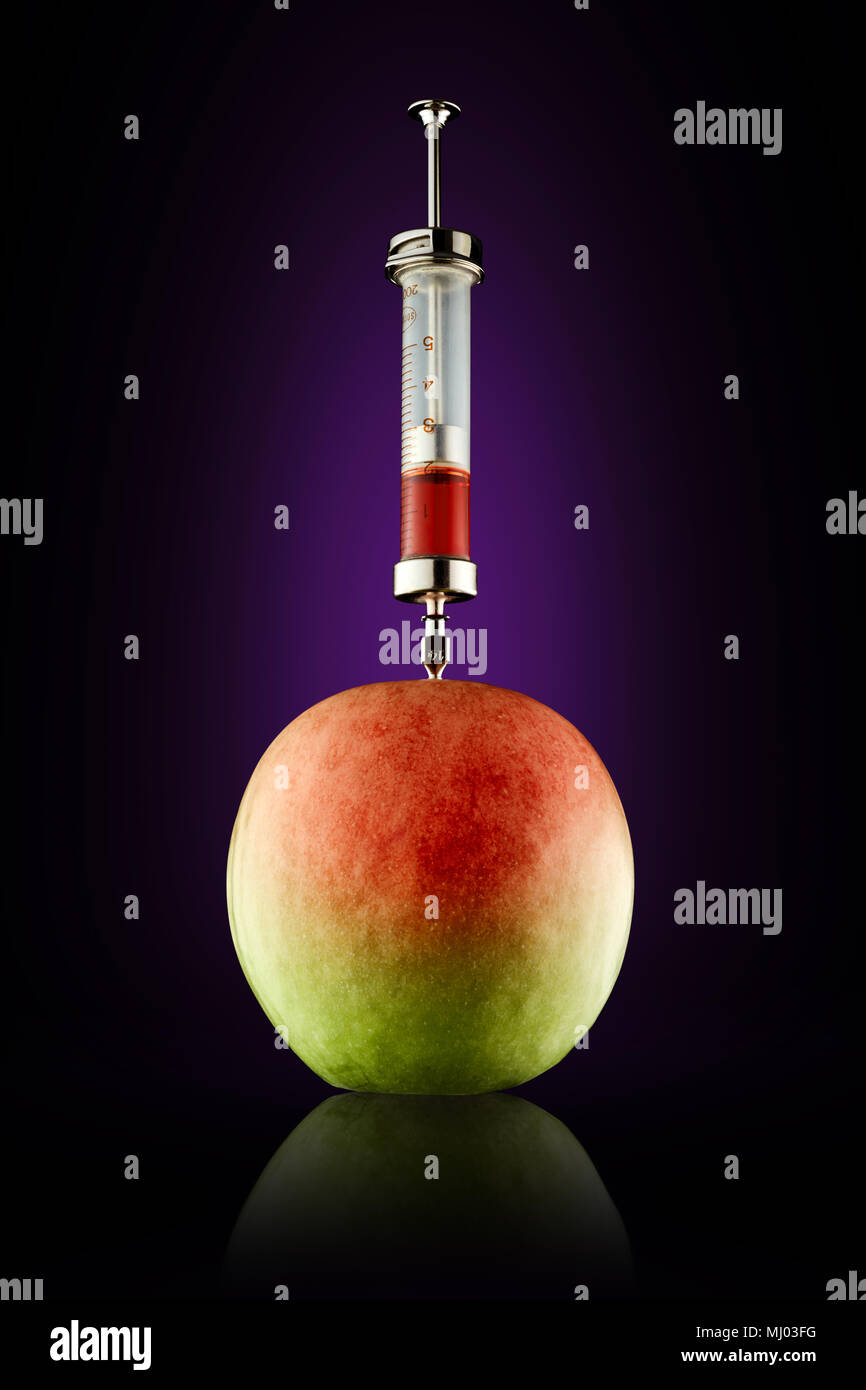 Syringe injecting red color to an apple. Concepts of genetic ...