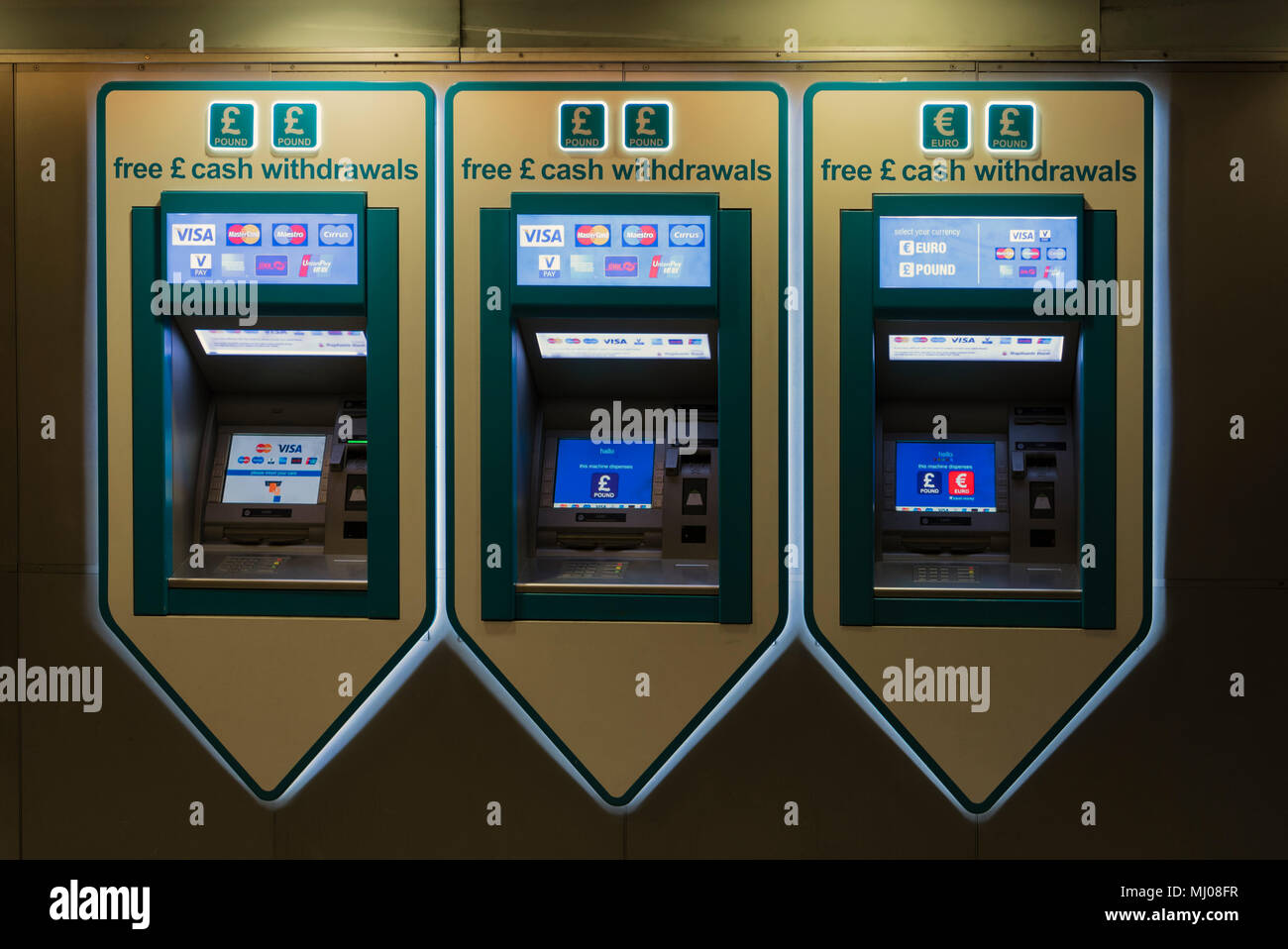 Cash withdrawl automated vending machines in a line, lit from overhead ...
