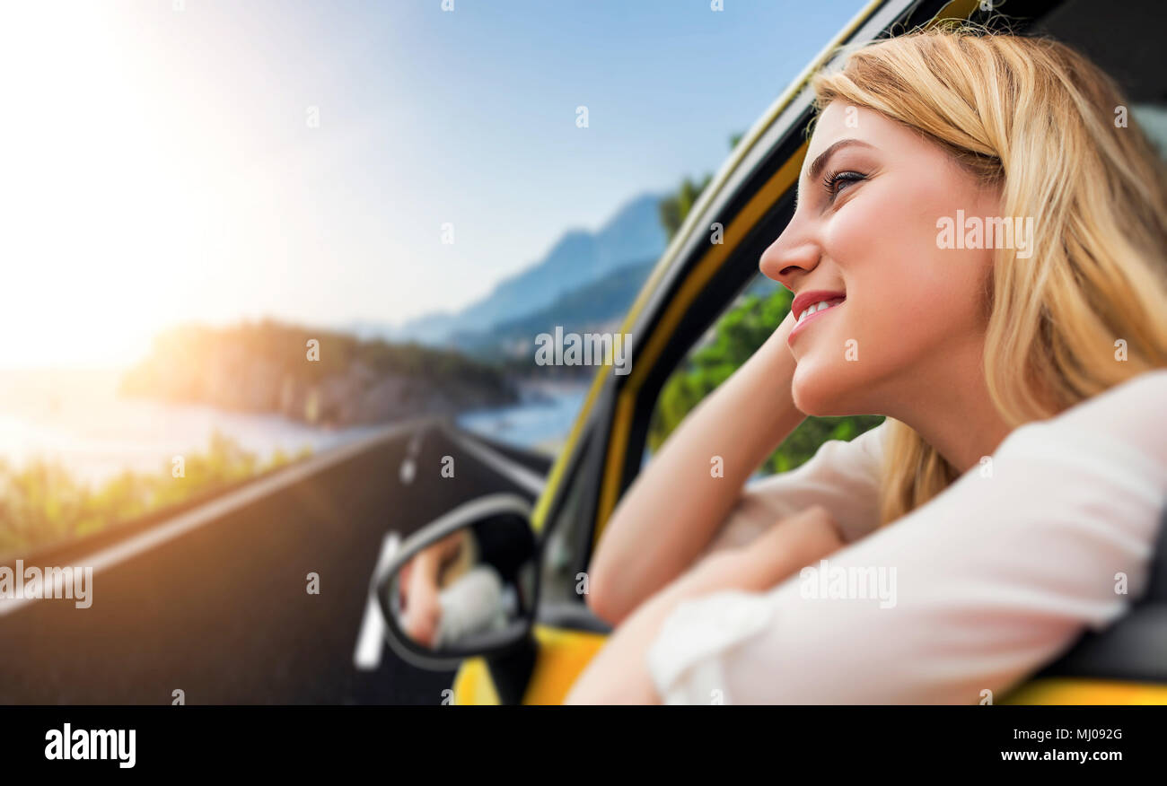 Travel or vacation. Beautiful blond girl in car on the road to the sea. Stock Photo