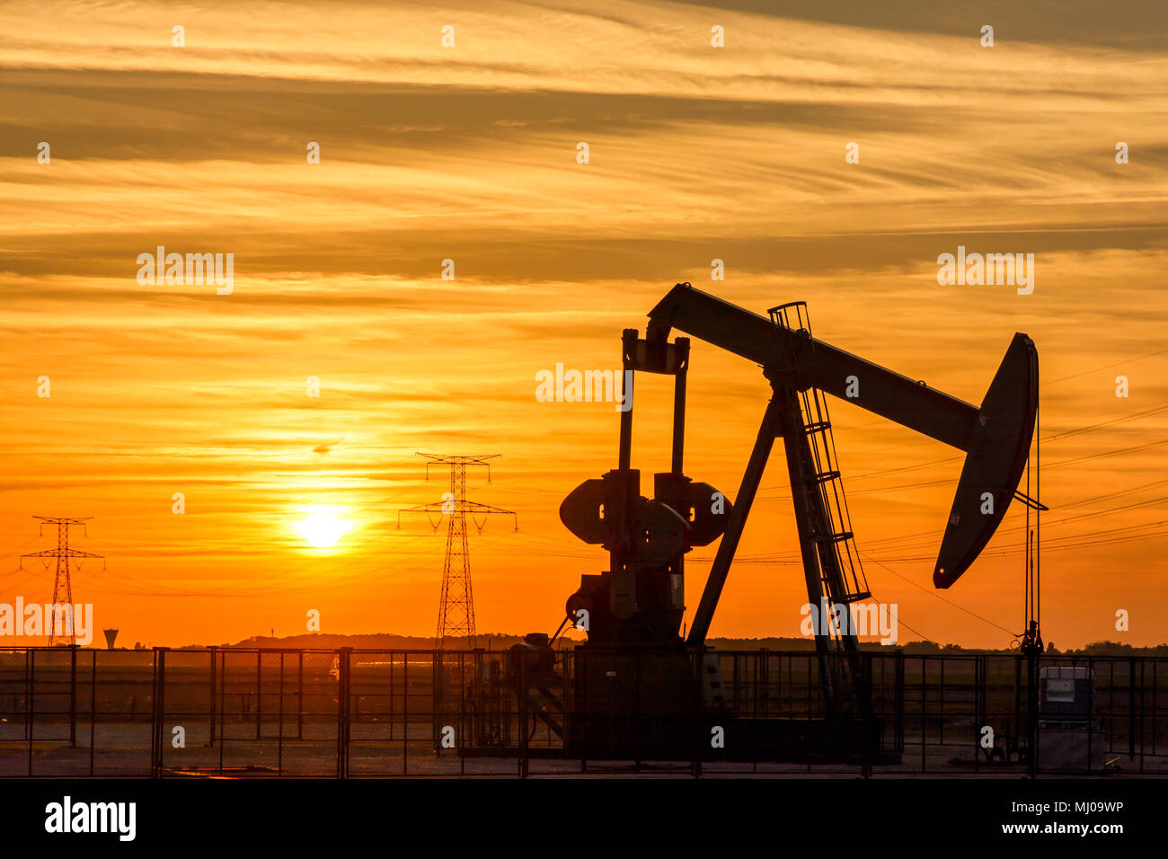 Pumpjack and transmission towers at sunset symbolizing energy
