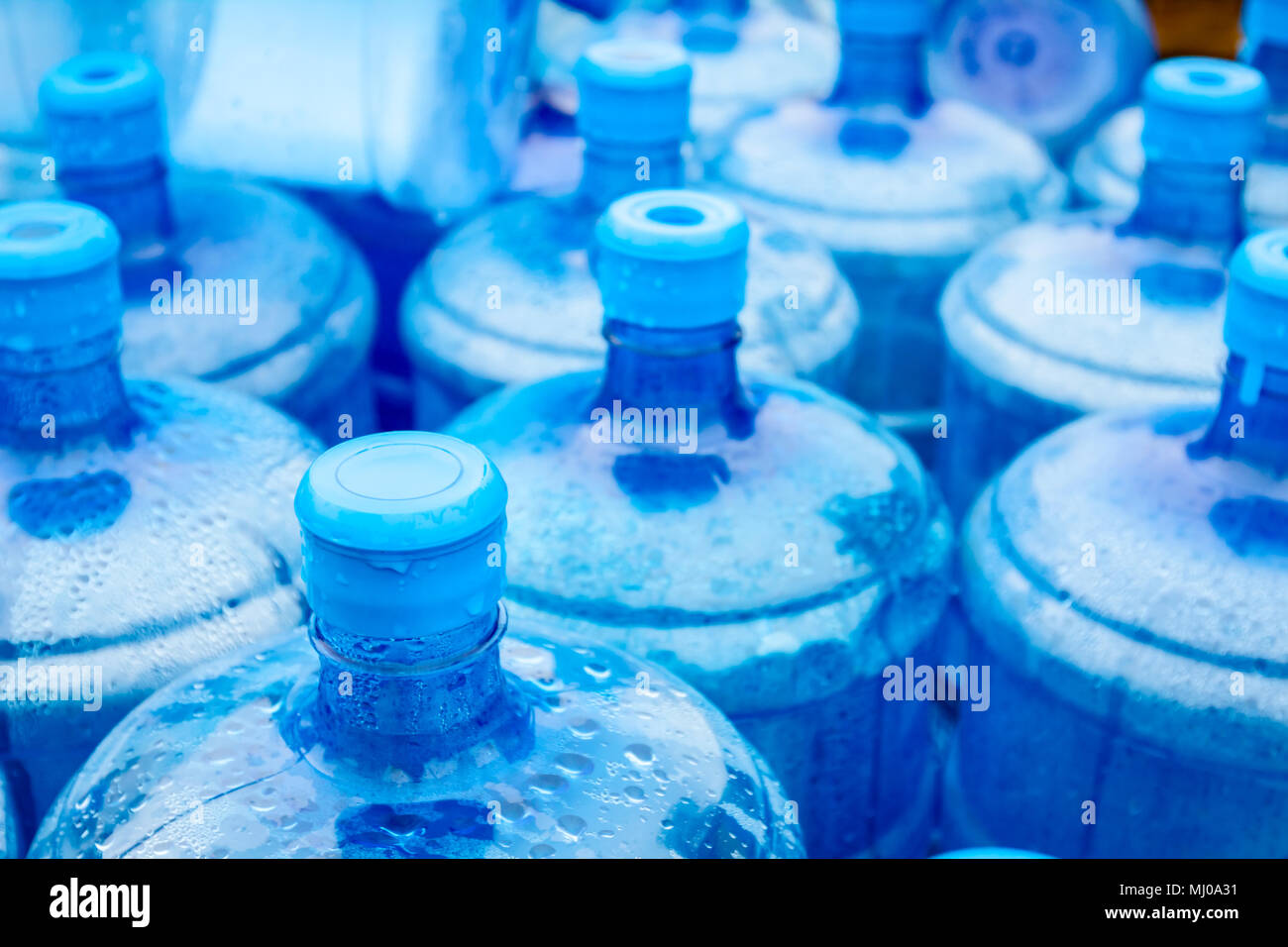 Big empty plastic water bottles for the cooler are stacked at outdoor warehouse. Stock Photo