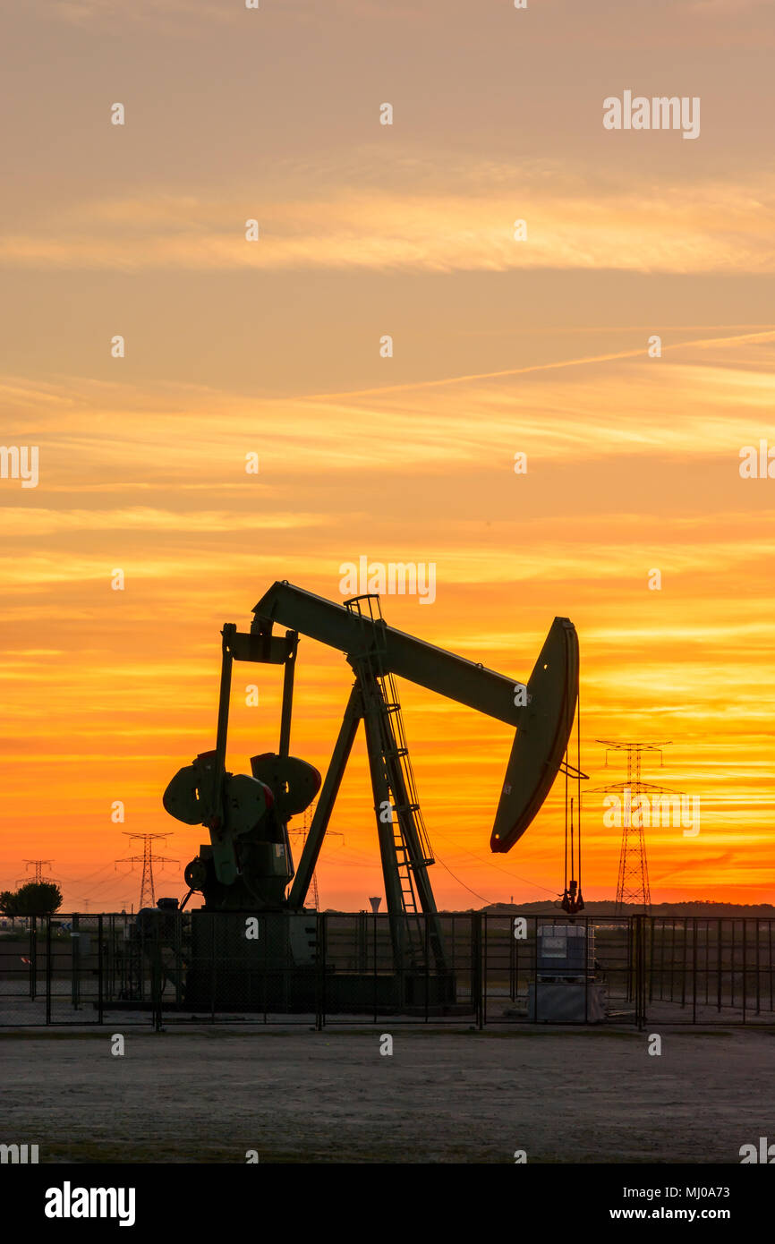 Pumpjack and transmission towers at sunset symbolizing ecological