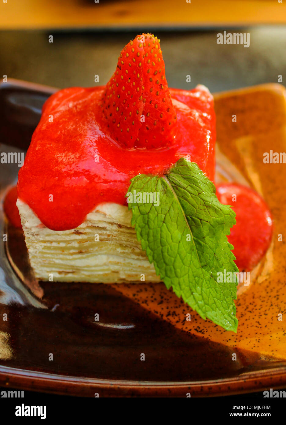 Sweet strawberry dessert, decorated with mint leaf on a square ceramic plate Stock Photo