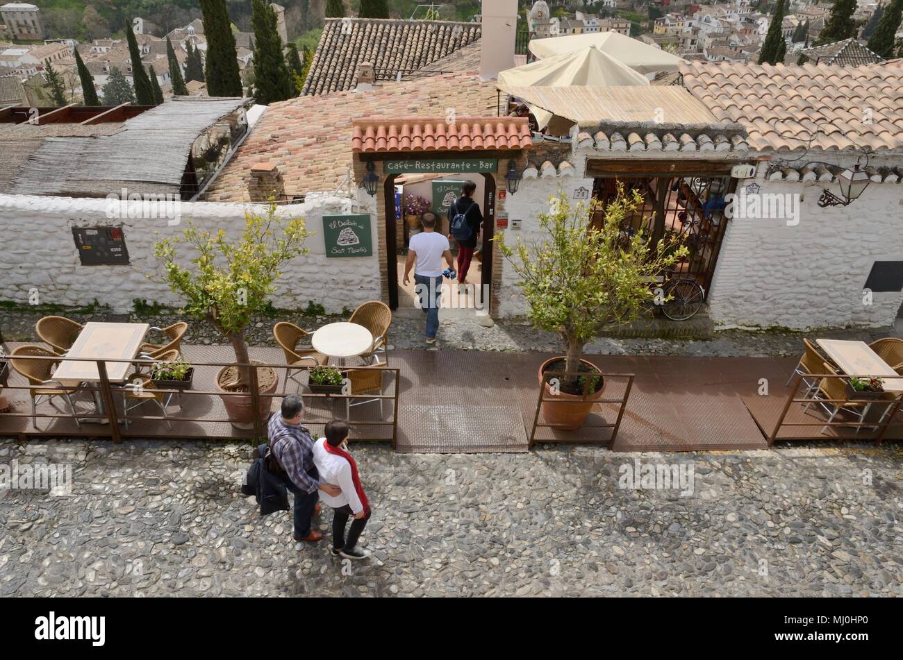People going into a restaurant seen from the viewpoint of Saint Nicholas  in the Albaicin district of   Granada,  Andalusia, Spain. Stock Photo